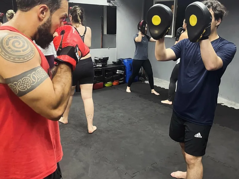 Professor segurando manoplas durante treino de chute na Arena ProFight
